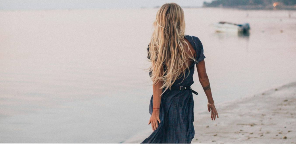 Eine Frau am Strand, die nach Weiblichkeit, Sinnlichkeit und Verbindung sehnt im Rahmen eines Yogaretreats